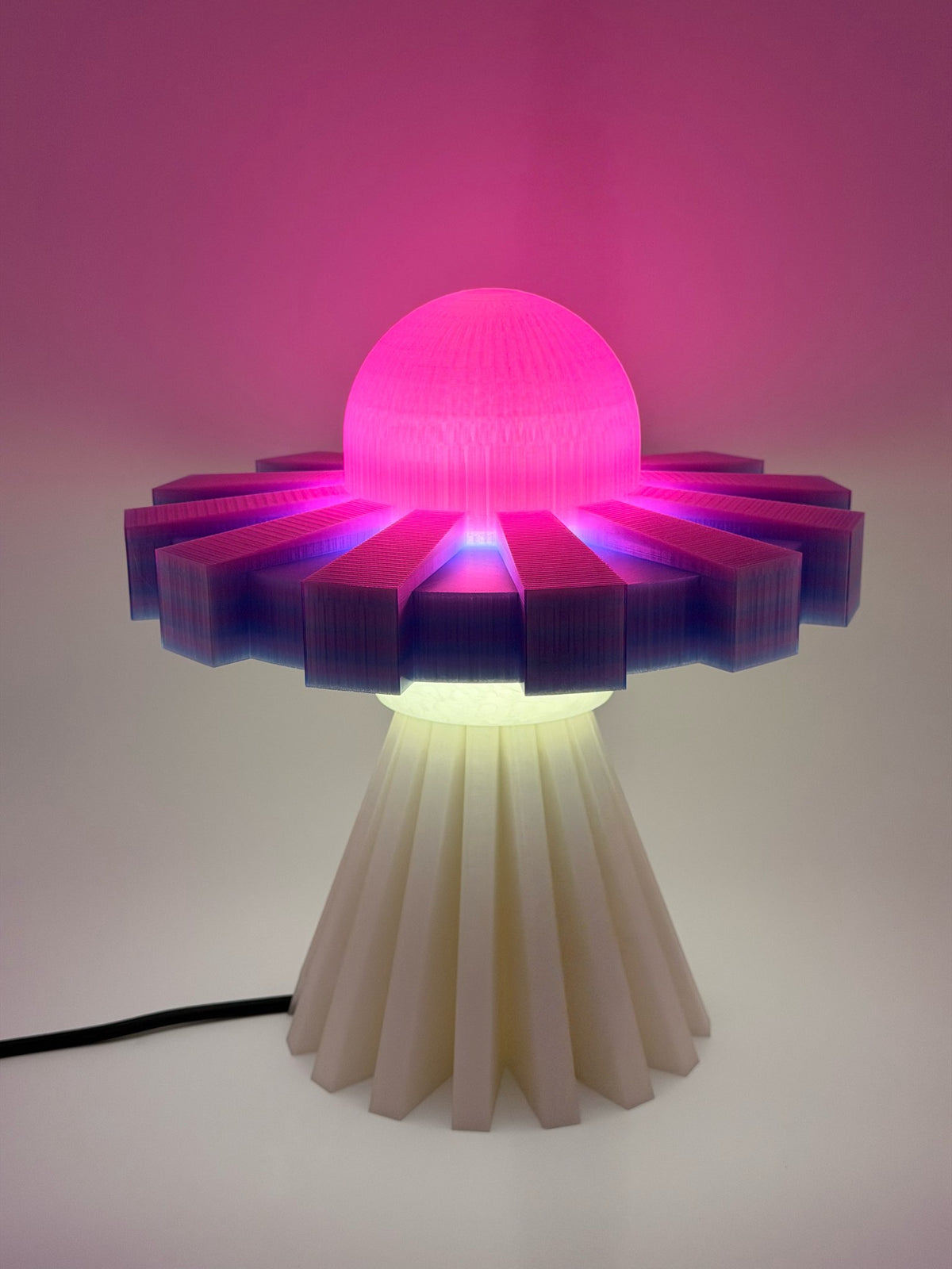Hot pink and lavender UFO lamp glowing against a pink wall