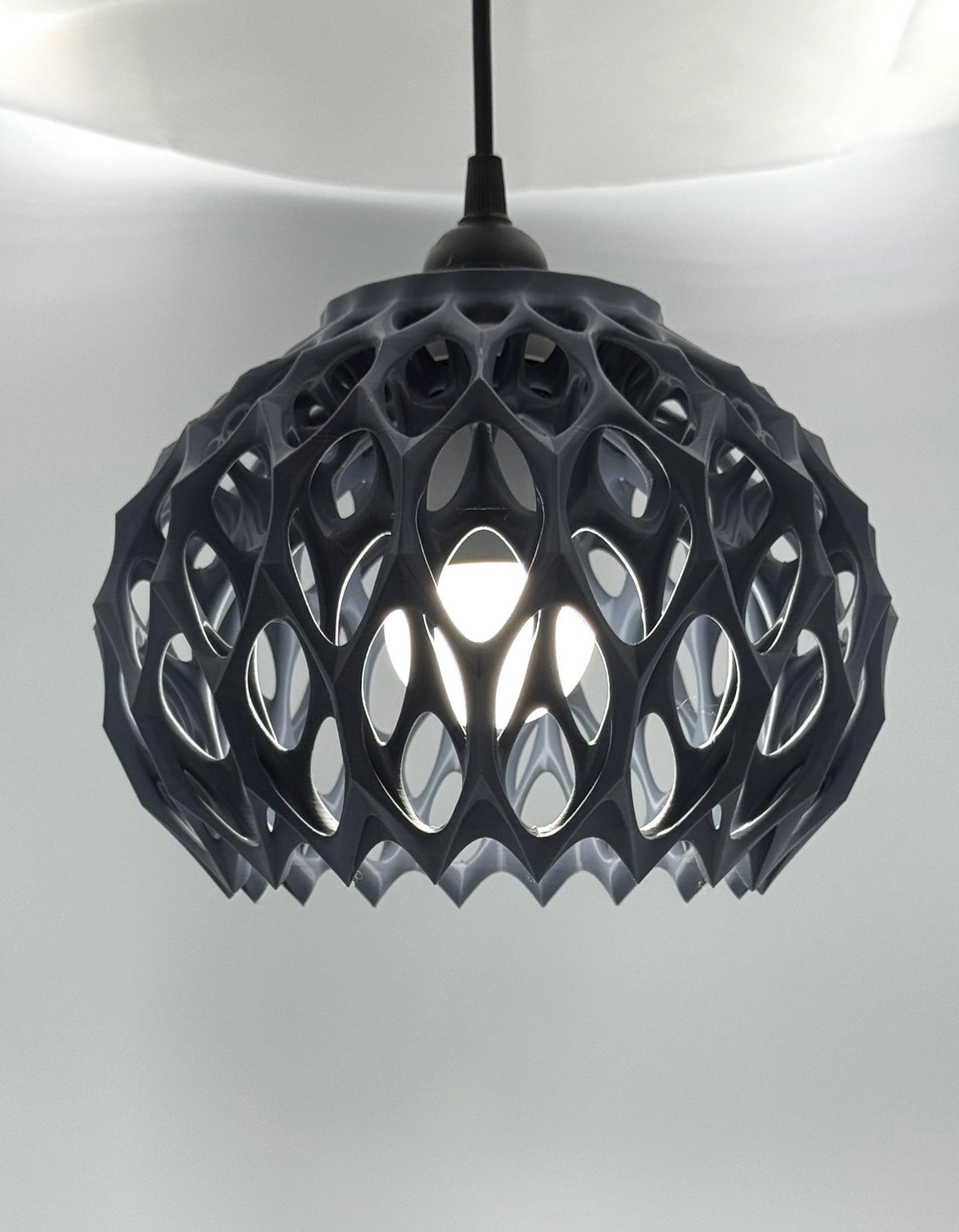 Gunmetal gray Alien Beehive 3D printed pendant lamp lit, with honeycomb lattice dome