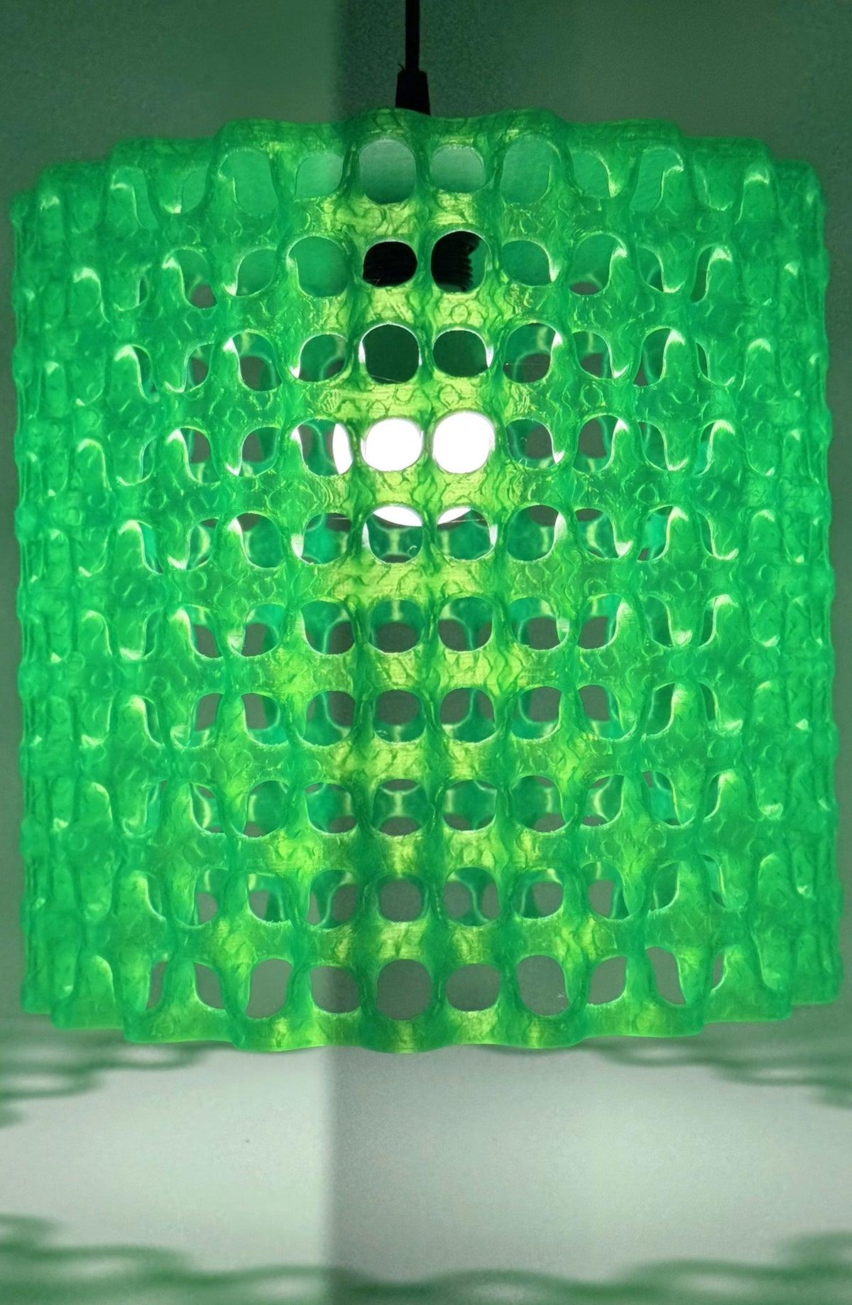 Alien Waffle neon green pendant lamp glowing and casting lattice shadows