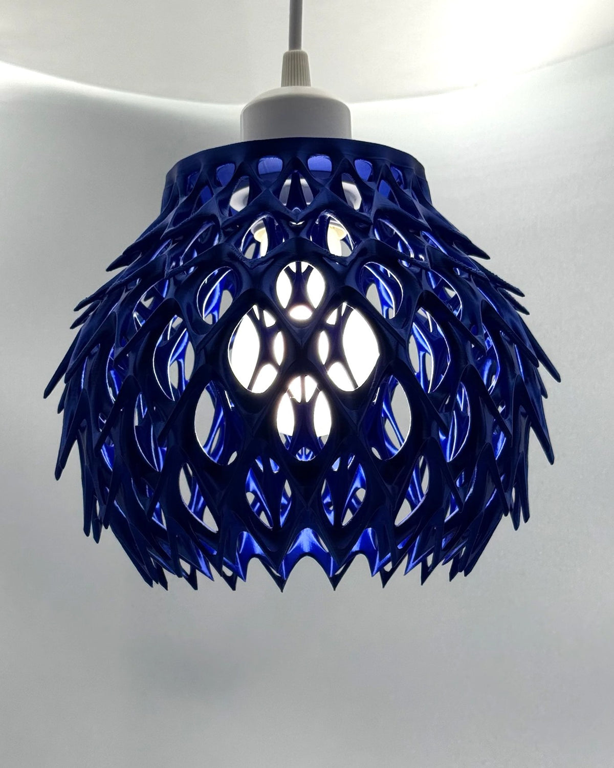 Cobalt blue Blue Alien Artichoke 3D printed pendant lamp with spiky petal lattice, glowing