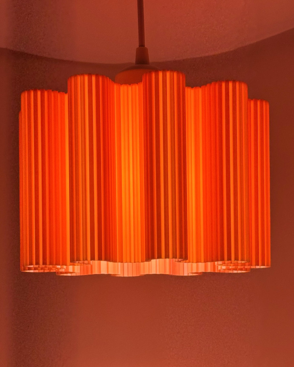 Orange Wave 3D printed pendant lamp glowing bright orange with fluted wave shade