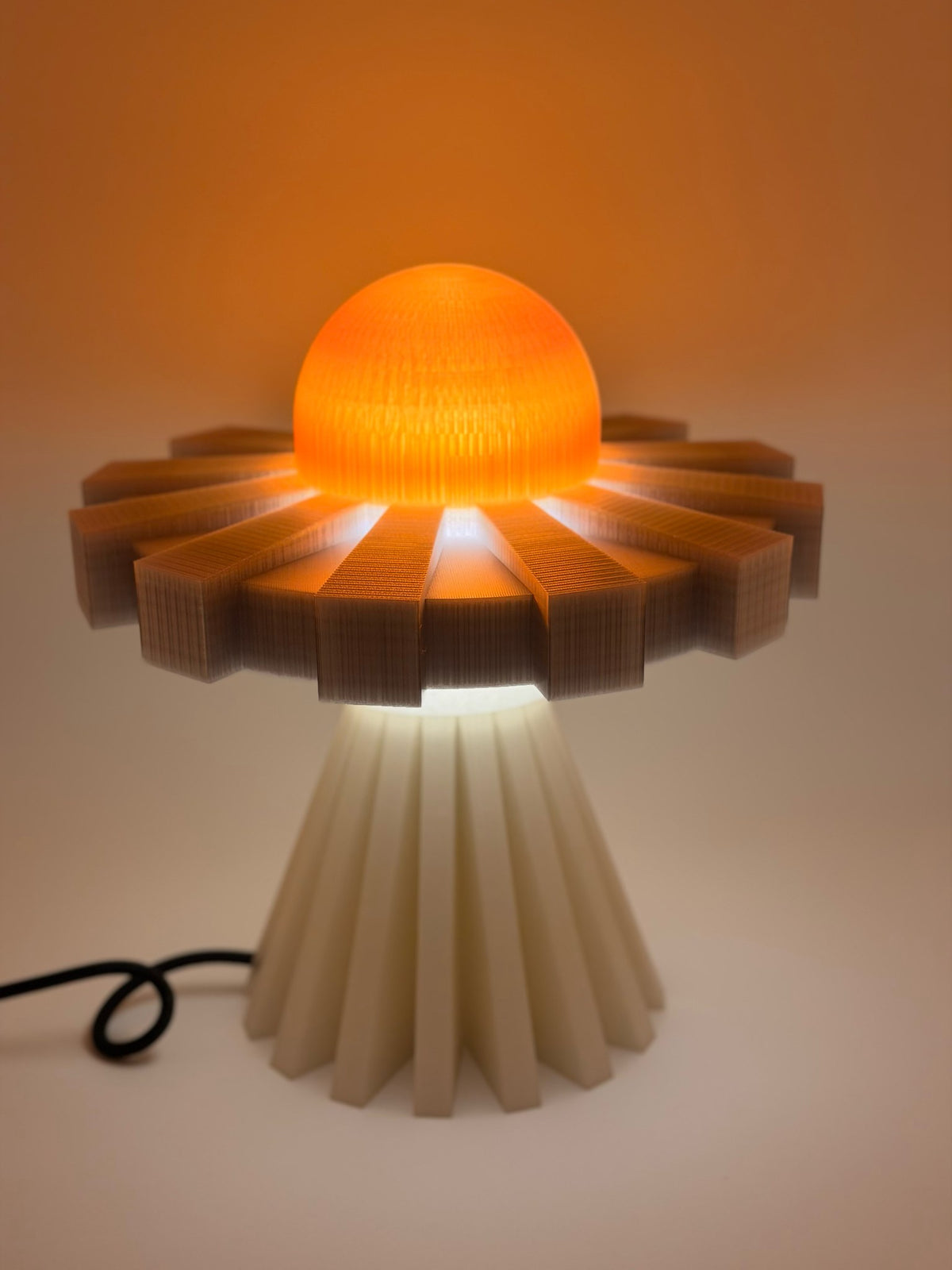 Tangerine and silver UFO lamp switched on with a glowing orange dome