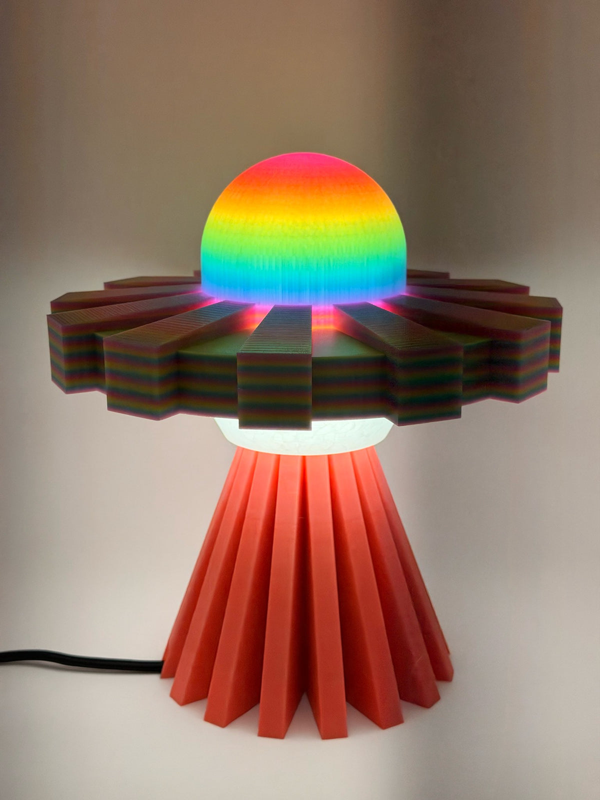 Rainbow and coral red UFO lamp switched on with glowing rainbow dome