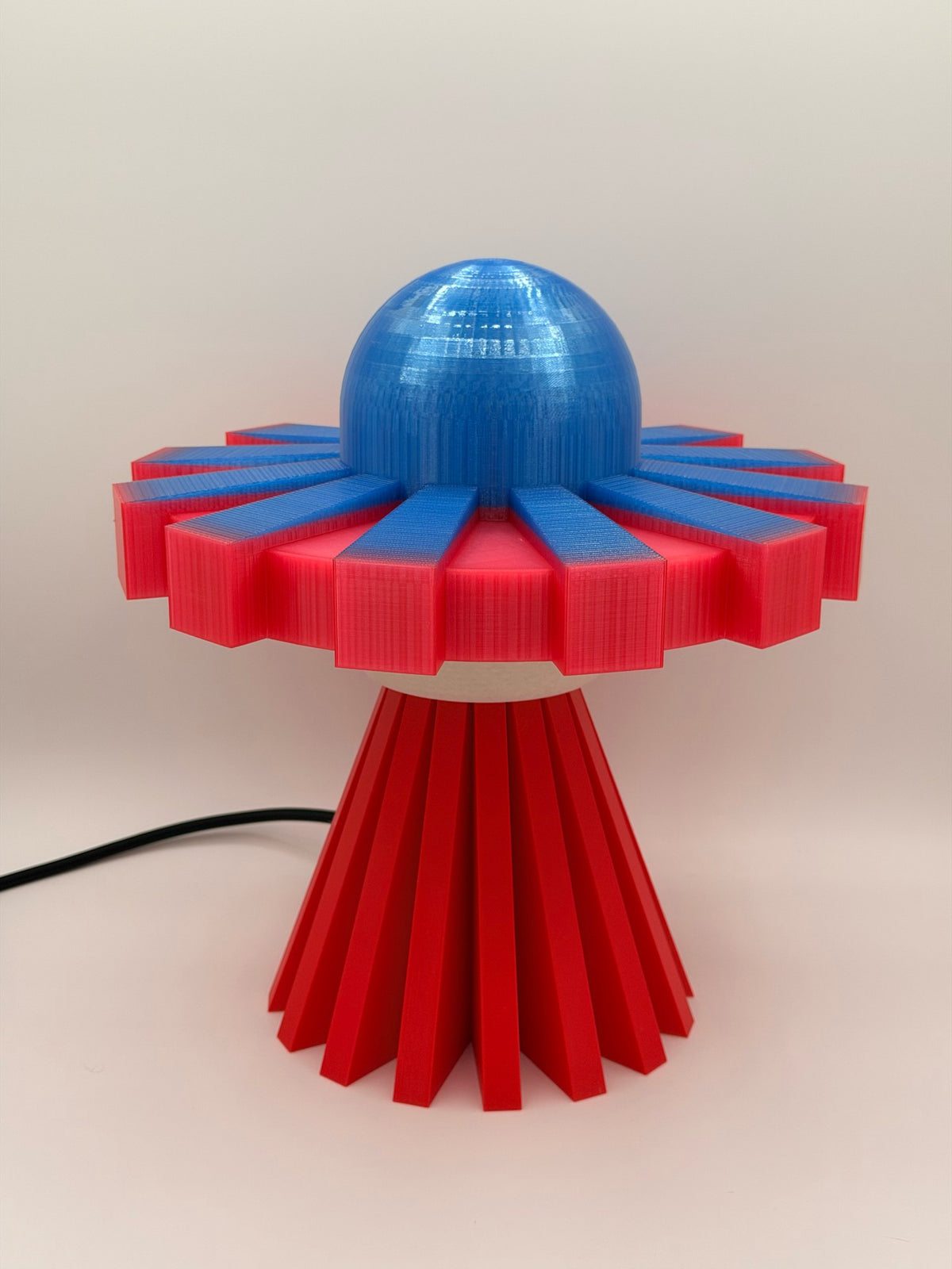 Red and electric blue 3D printed UFO lamp with blue dome, red saucer and red base