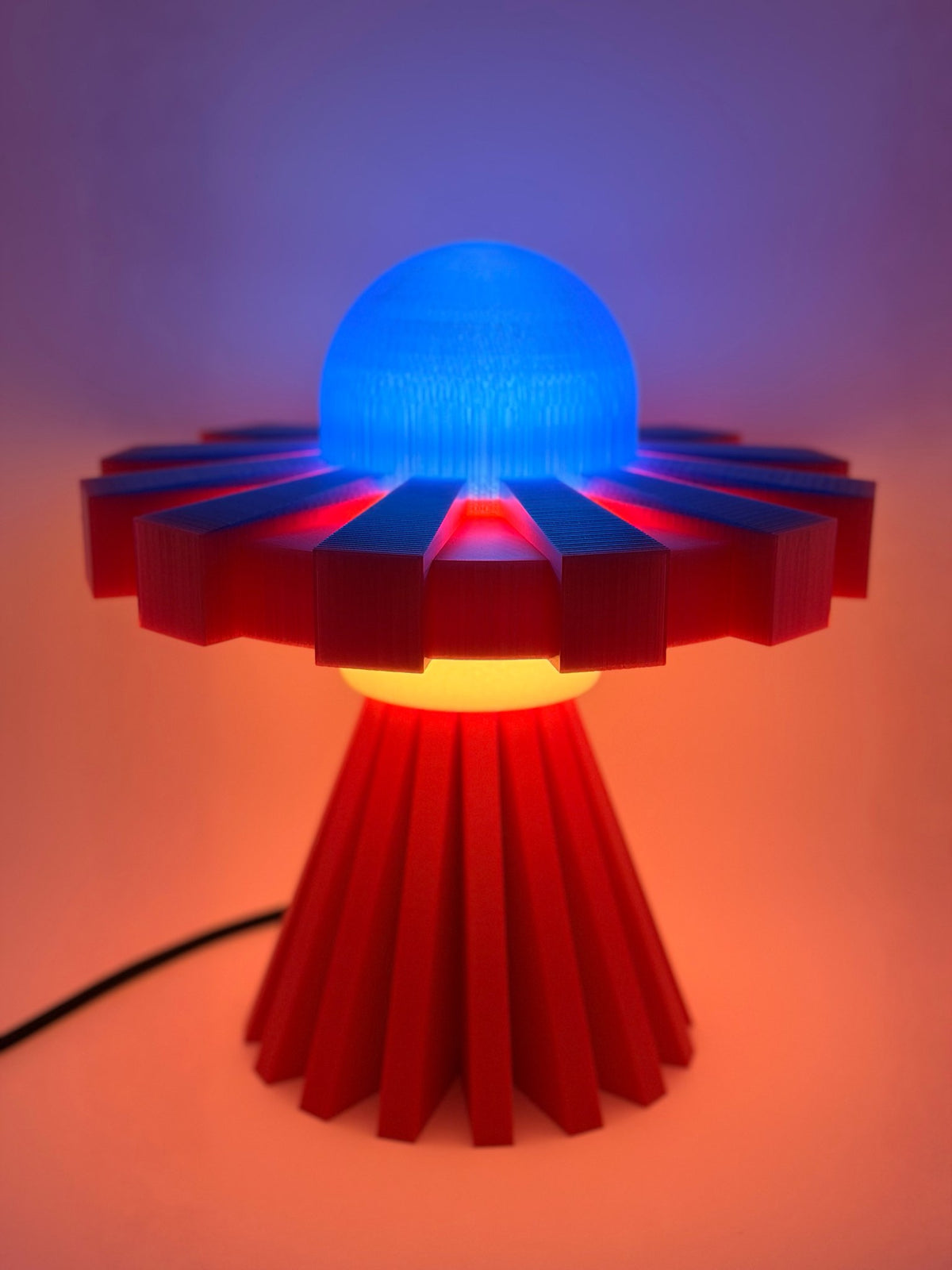 Red and blue UFO lamp switched on with glowing blue dome and red light