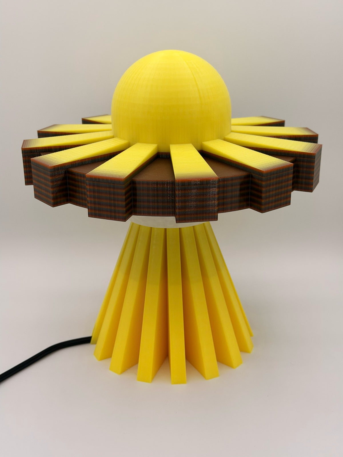 Golden yellow 3D printed UFO lamp with yellow dome, yellow and black saucer and yellow base, lamp off